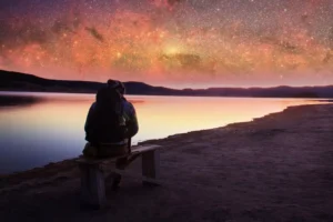 a man sitting under the night sky, thinking about his purpose