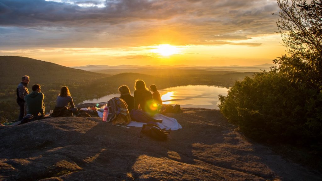 group of friends sitting on mountain during golden hour