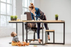 a woman on the phone in her home office smiling at her baby sitting on the floor - she balances career and family