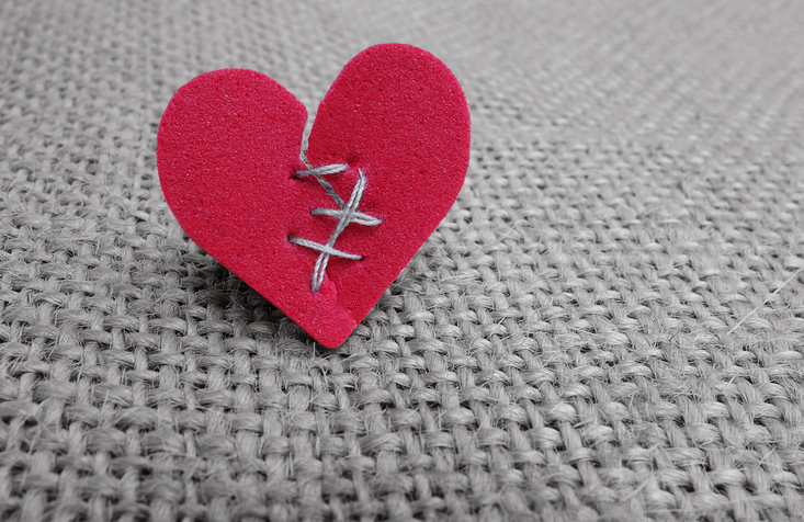 Broken red heart with white thread stitches