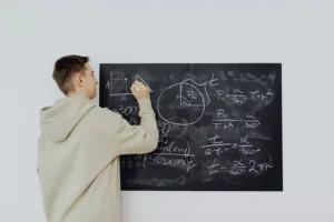 a man writing a math formula on a chalk board