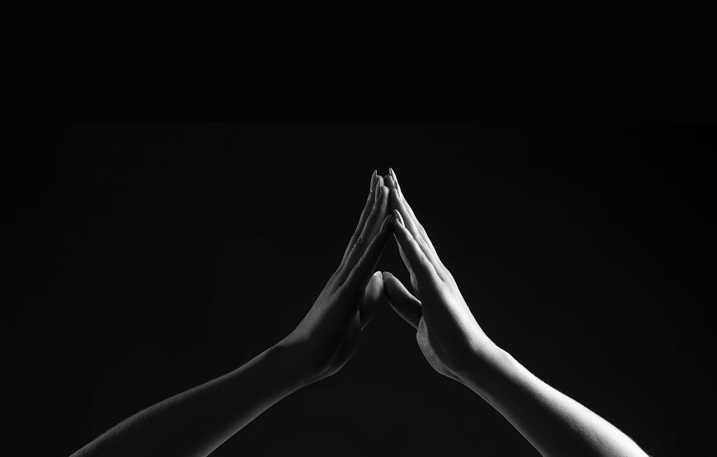 two hands touching in darkness
