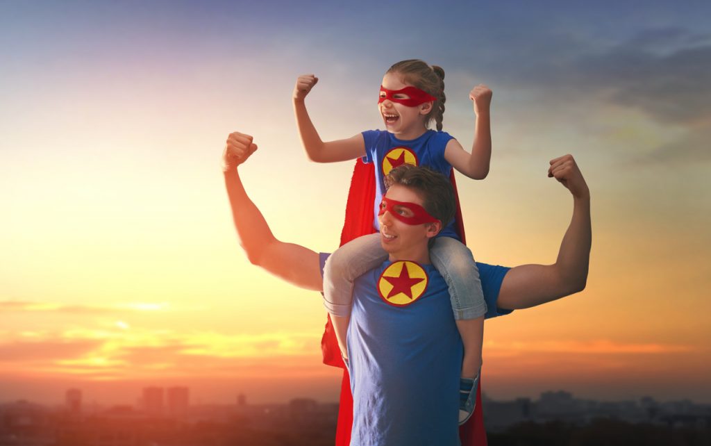 Dad with daughter on his shoulders - both dressed as super heros