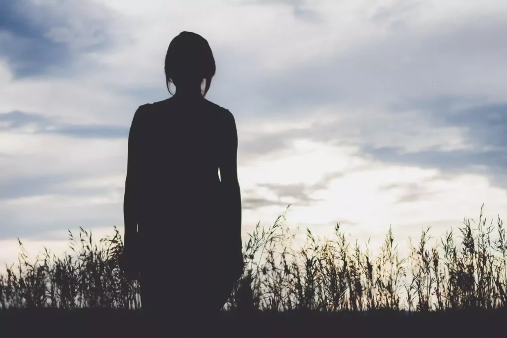 silhouette of a woman heading towards a sunny field, stepping out of the shadow of her parent's divorce
