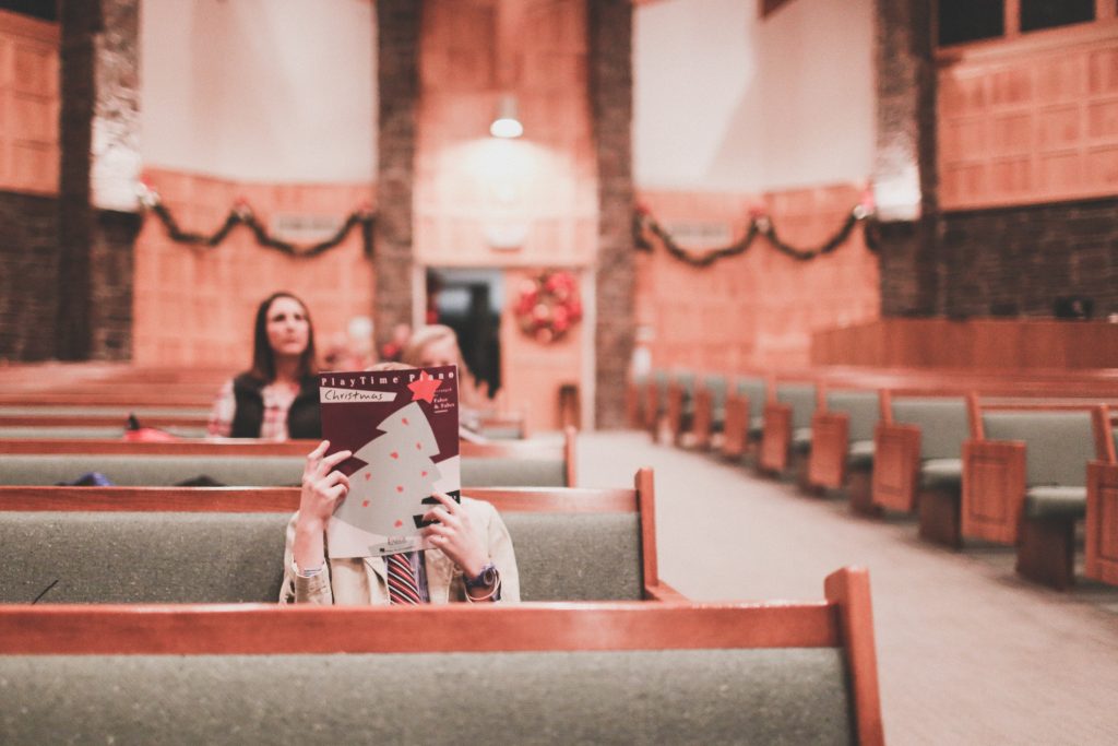 woman sitting in church sanctuary with a magazine covering her face