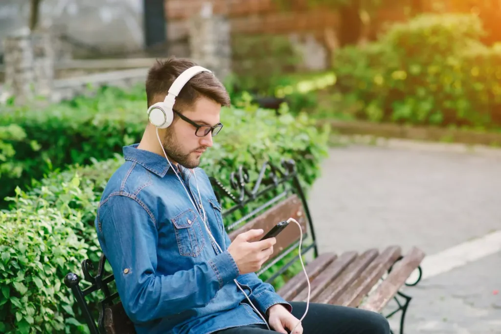 man sitting on a bench with headphones on listening to Christian music