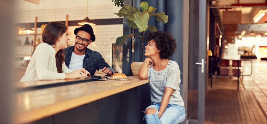 married couple talking to a single friend over a kitchen counter, friends after marriage