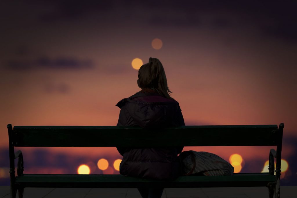 woman sitting on bench looking at the city, nighttime.