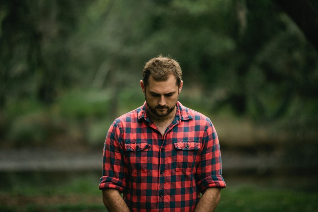 man standing outside, with head bowed