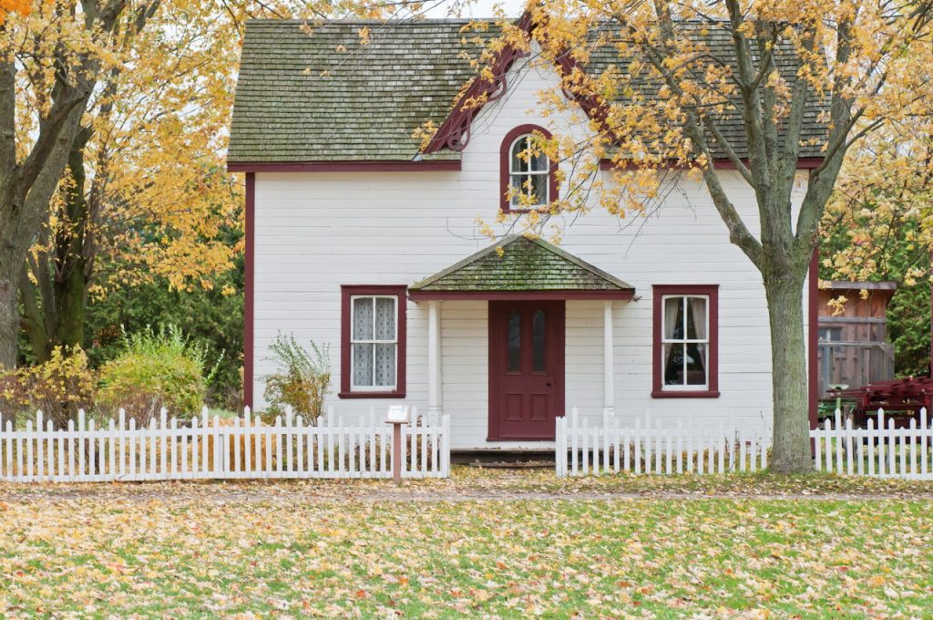 cute, small house with a white picket fence
