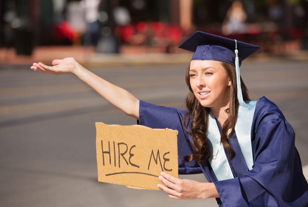 a college grad holding a "Hire Me" sign