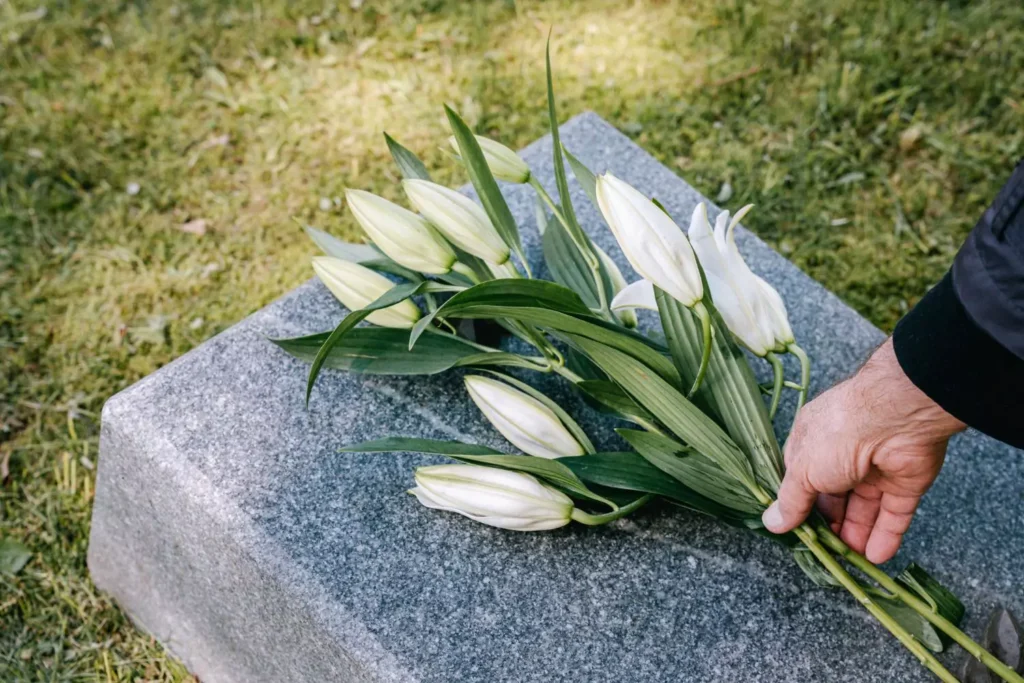 a man putting flowers on a tombstone. We were never meant to die.