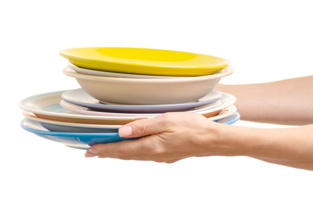woman holding stacked plates and bowls