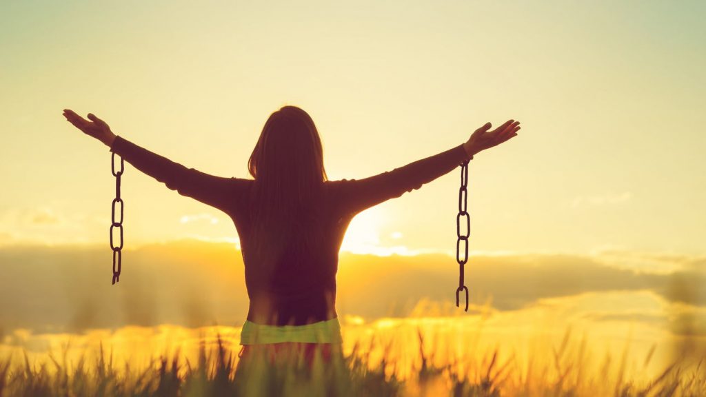 woman standing with arms outstretched, chains broken