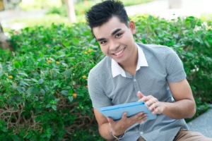 nice guy in front of a bush holding an iPad
