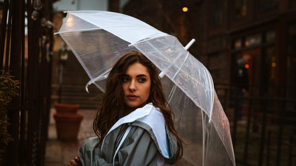 young woman standing alone, holding an umbrella