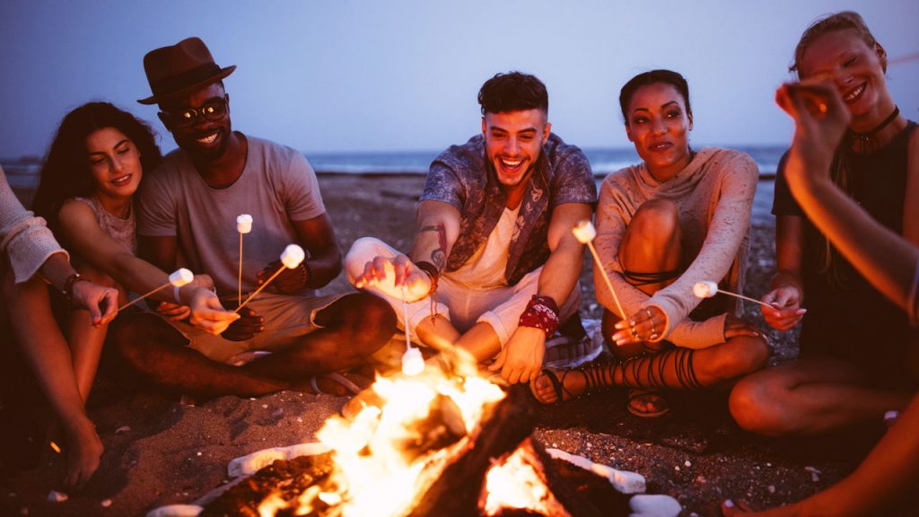 friends sitting around a bonfire, one dating couple sitting close