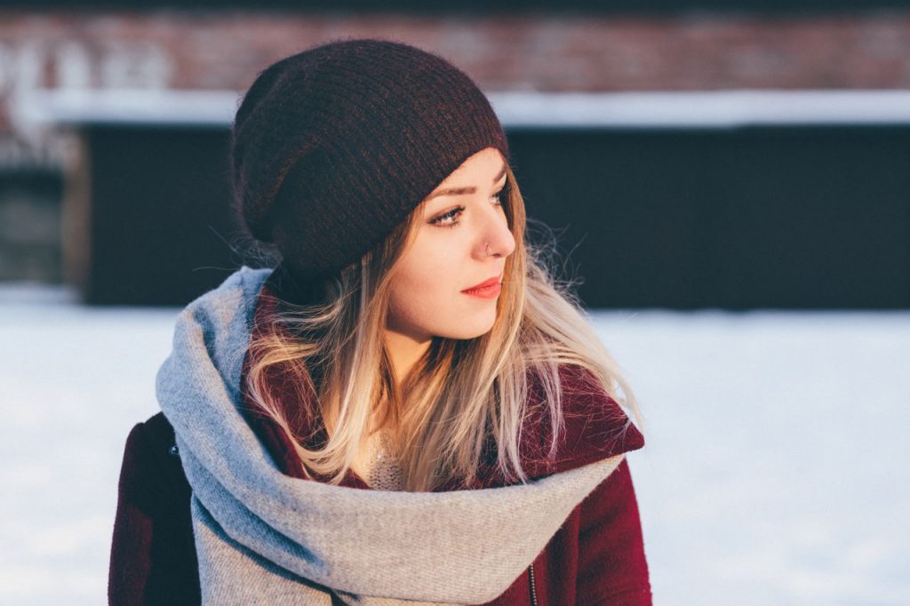 woman standing alone, contemplative, wearing winter coat and beanie