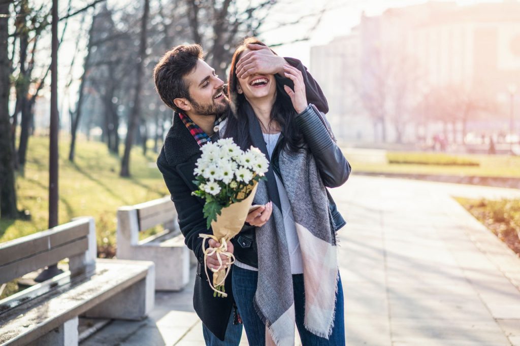 boyfriend surprising girlfriend with bouquet of white daisies