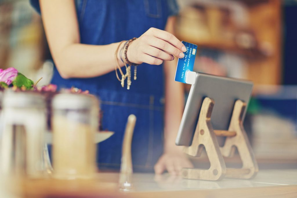 barista swiping credit card on tablet payment