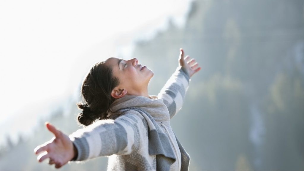 woman with arms open looking toward sky outside during winter