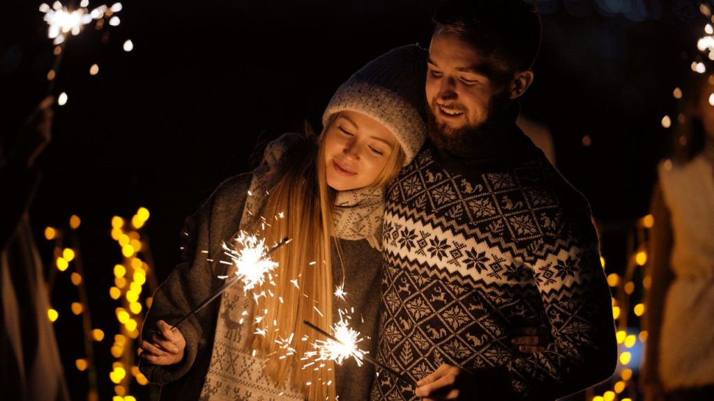Couple holding sparklers in winter