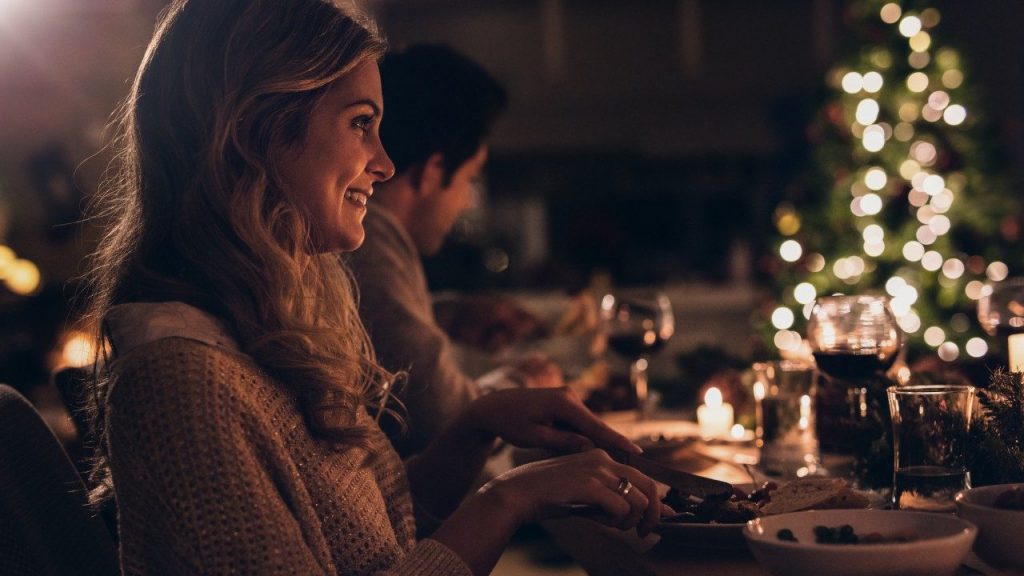 woman sitting at dinner table smiling during the holidays