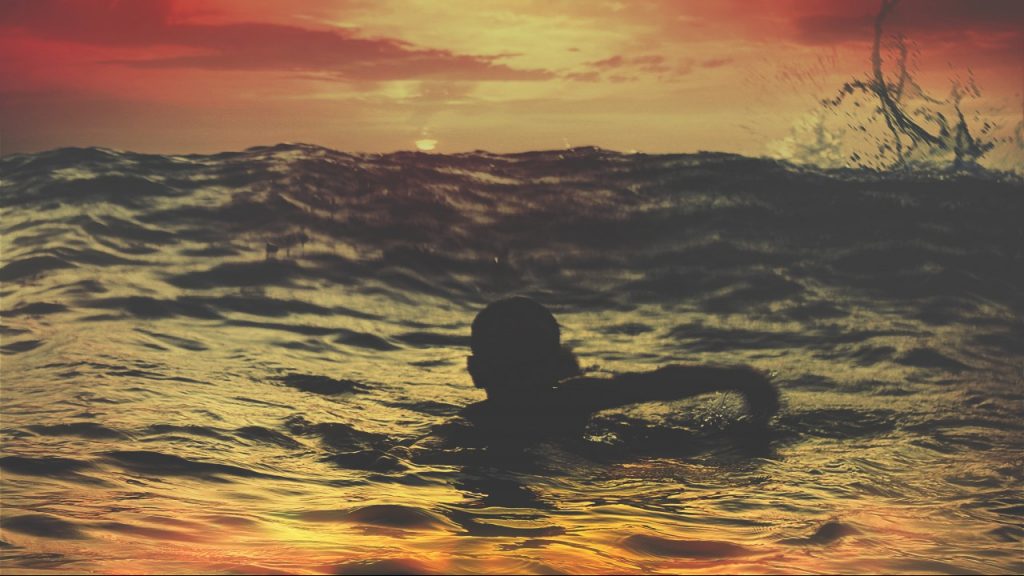 person swimming in ocean during sunset