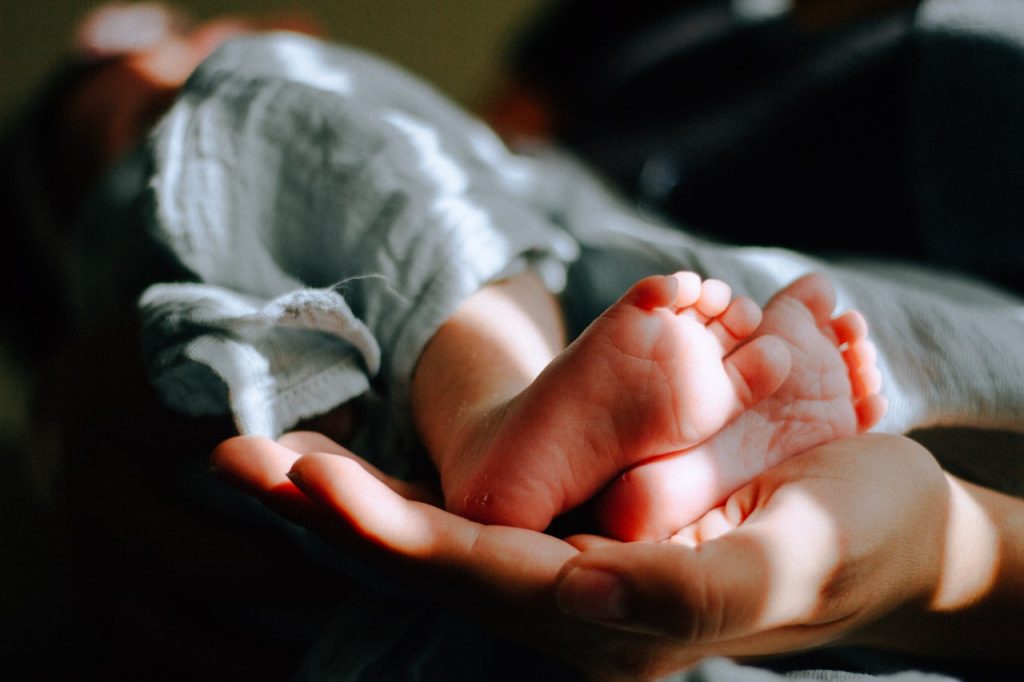 person hold a baby with focus on the baby's feet