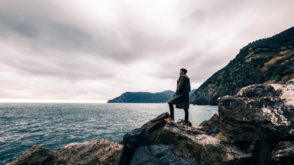 man standing on rocks overlooking ocean