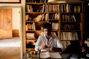 a masculine man writing in a journal
