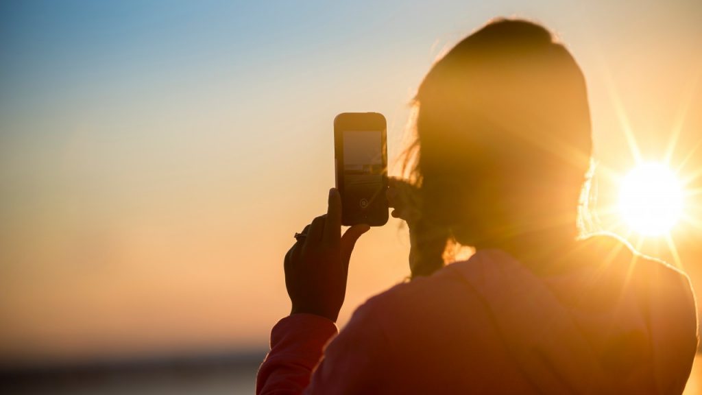 woman taking picture of sunset