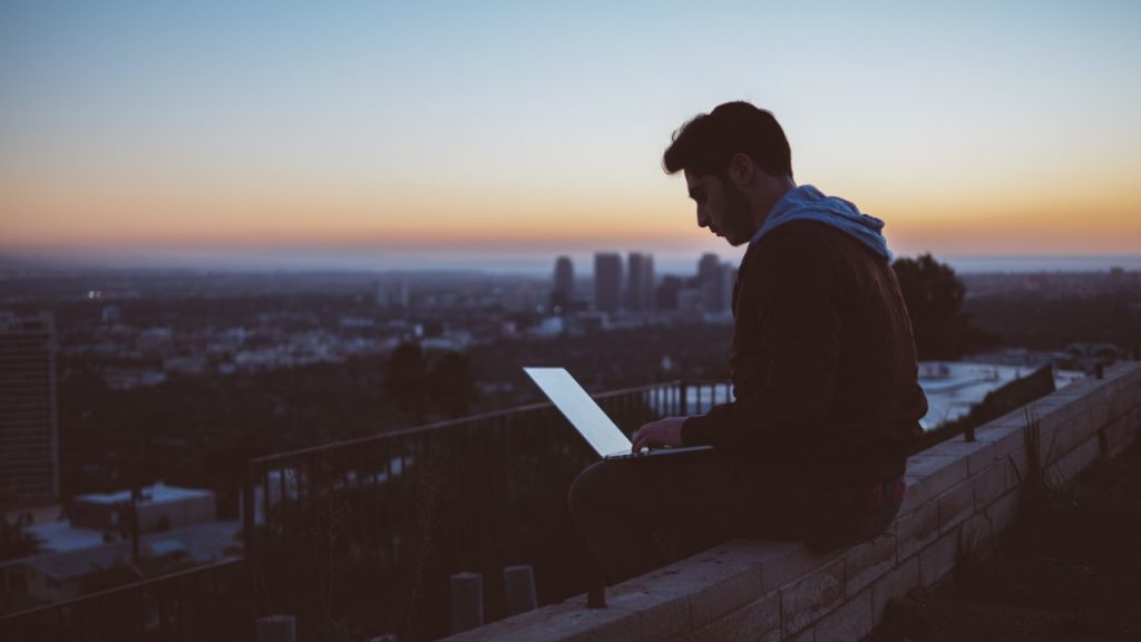 man working on computer with sunset in background