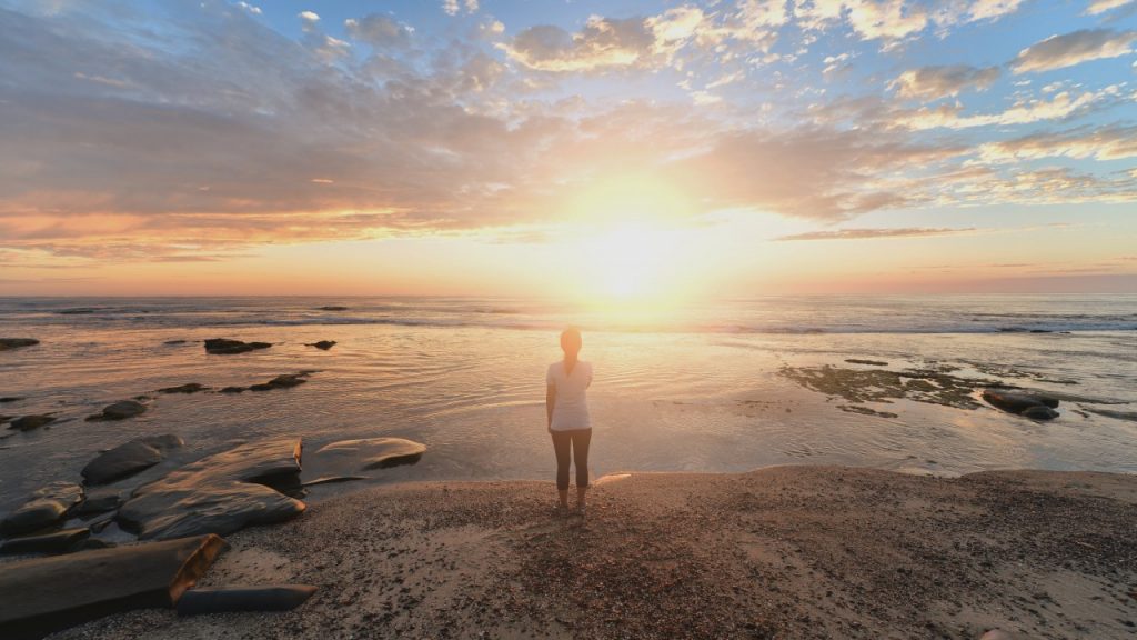 woman standing on beach during sunrise