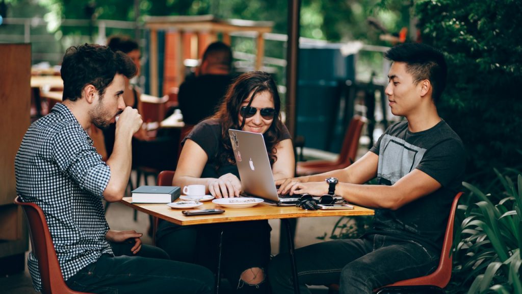 people sitting at cafe table with computer