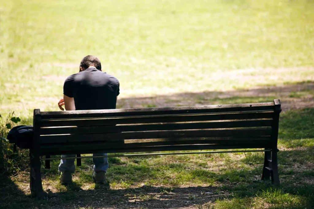 man sitting on a bench with his head down suffering a crisis of faith