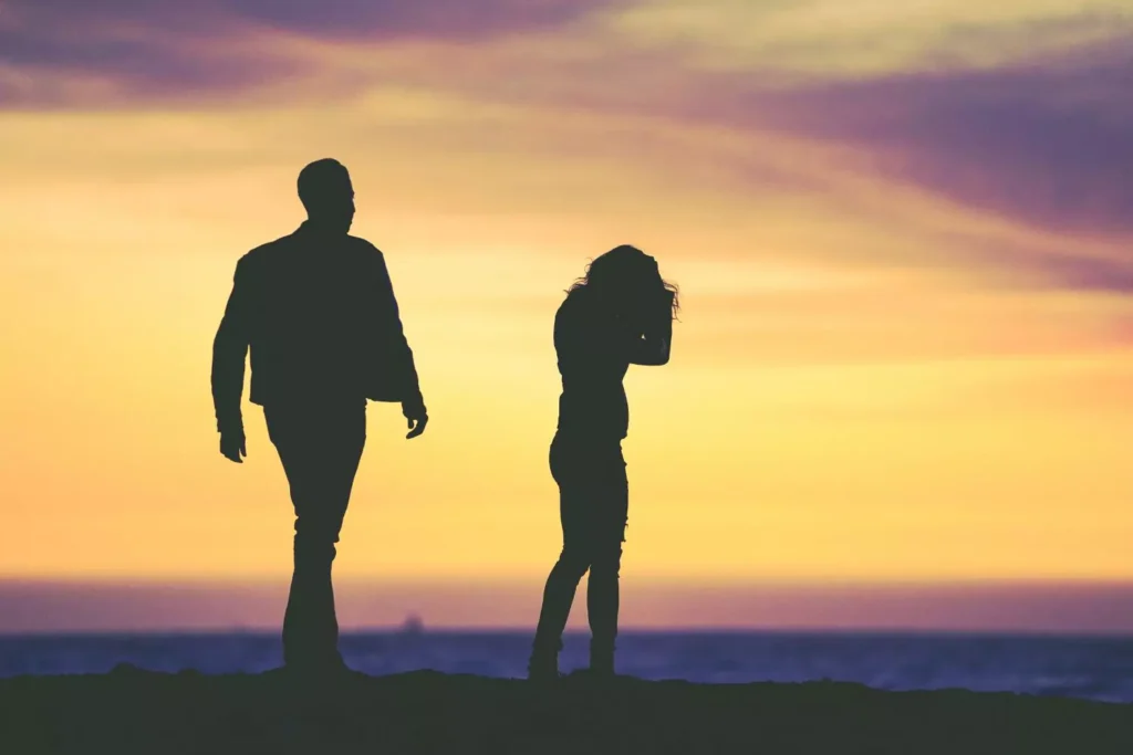 a man and a woman walking on the beach, having conflict