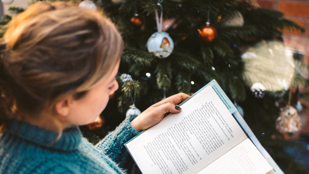 woman reading by christmas tree