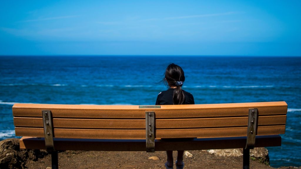 woman sitting by blue ocean