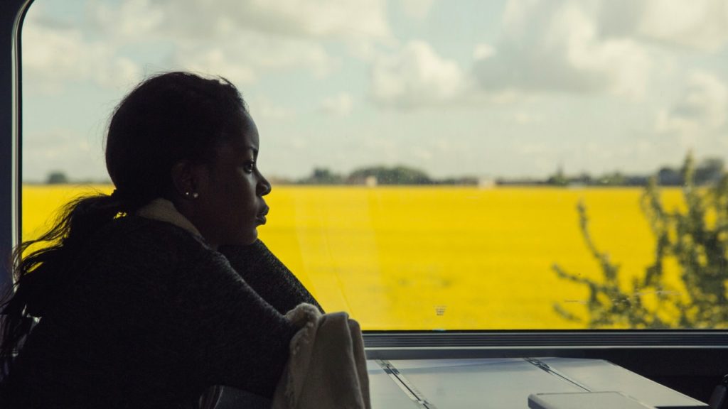 woman on train and yellow field