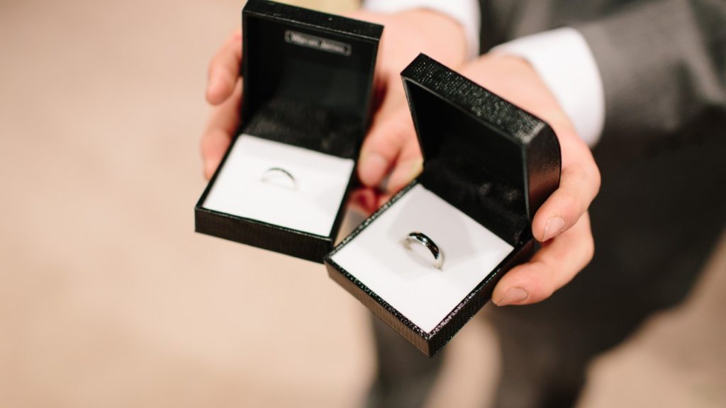 man holding wedding rings in boxes