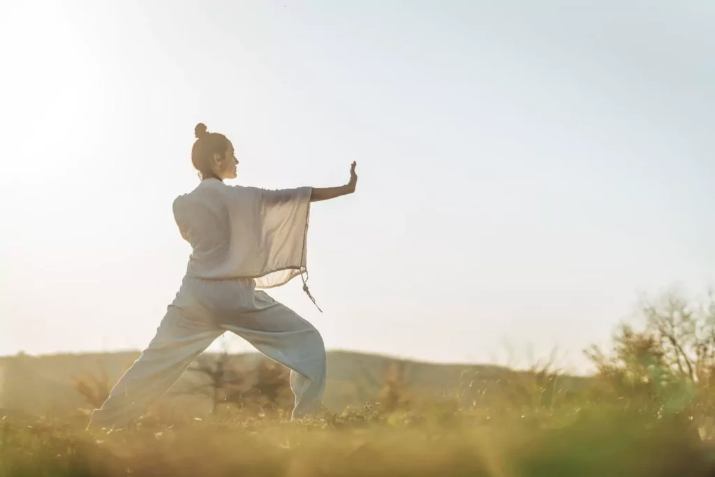 woman doing martial arts in a grassy field. A disciplined life.