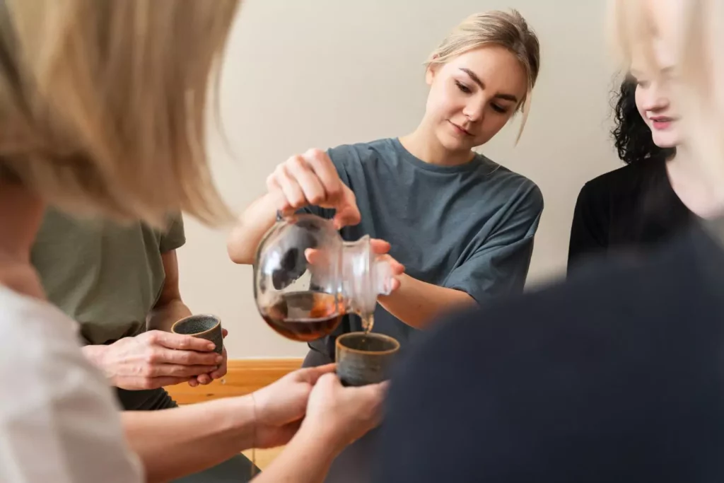 woman pouring tea into friends cups showing hospitality