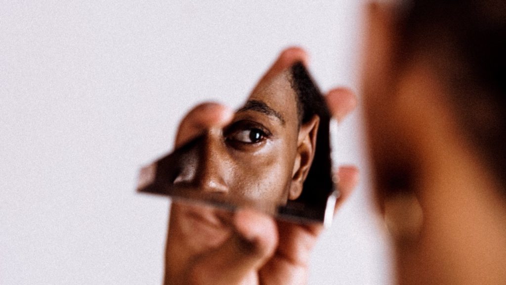 man looking through broken mirror