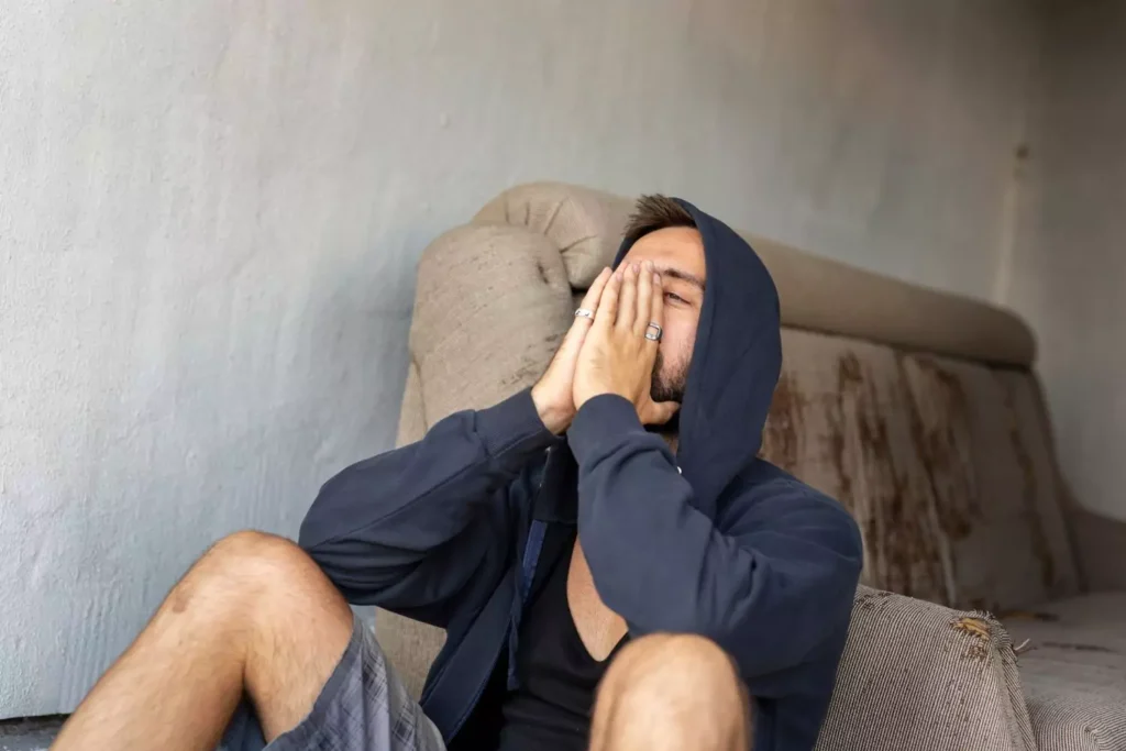 A man sitting on the ground in anger with his hands in front of his face