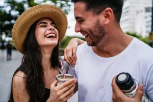 woman with her hand on her boyfriend's shoulder, laughing and holding coffee. vulnerability