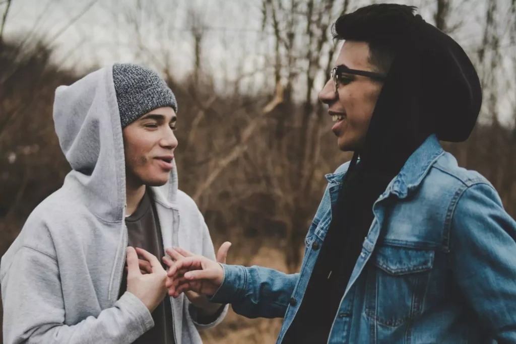 Two guy friends talking to one another, one of them offering praise to the other