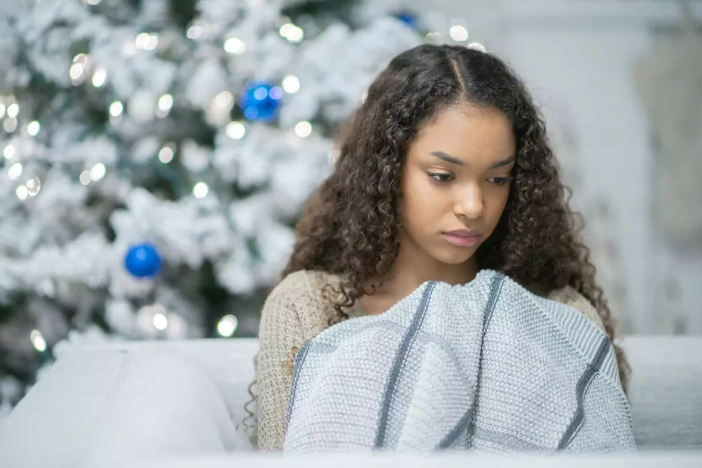 woman looking sad in front of a Christmas tree, lonely