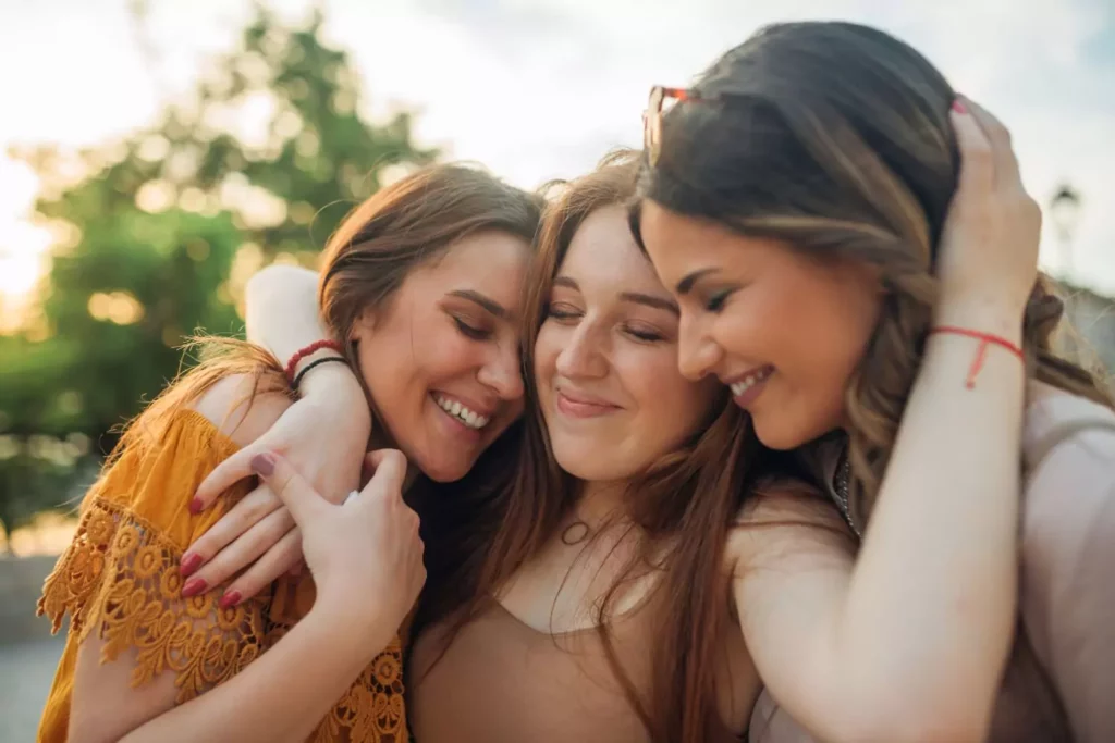 three female friends hugging - positive touch