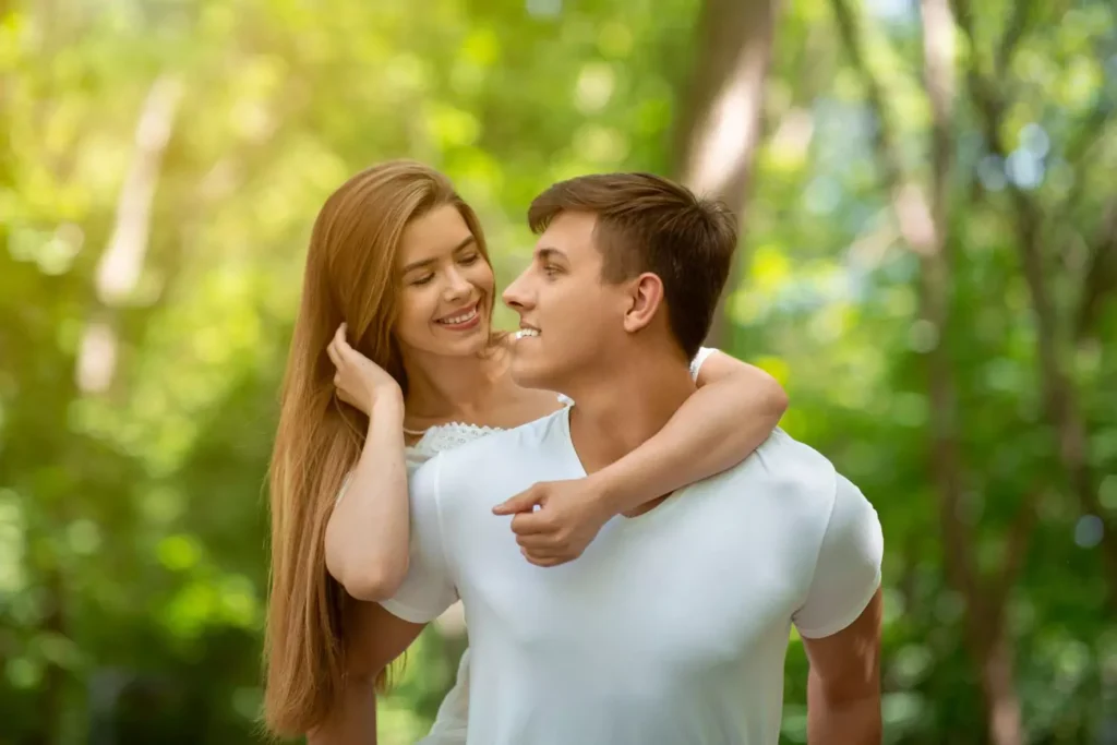 guy giving girl a piggy back and looking lovingly at each other. Winning a woman's heart